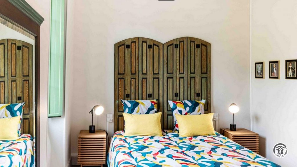Chambre double lumineuse avec lit double, linge de lit coloré et décoration soignée.