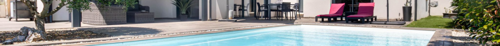 Piscine extérieure dans un hébergement touristique avec terrasse aménagée et espaces de détente.